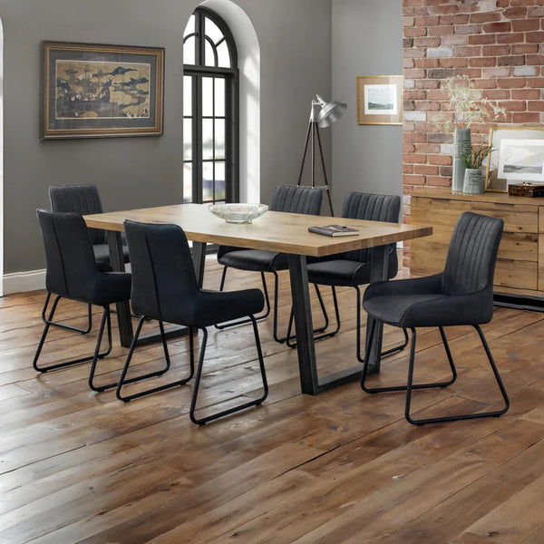 Dining room with wooden table and black chairs against a brick wall.