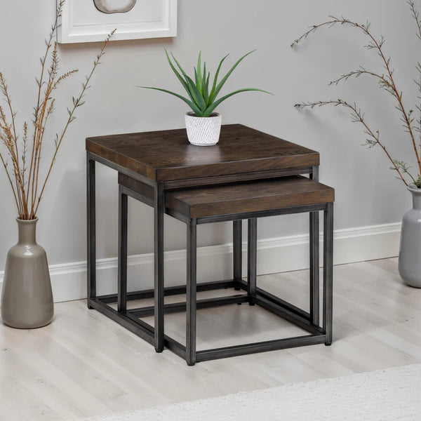 Set of two wooden nesting tables with metal legs in a room setting.