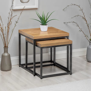 Set of two wooden nesting tables with metal legs in a room setting.