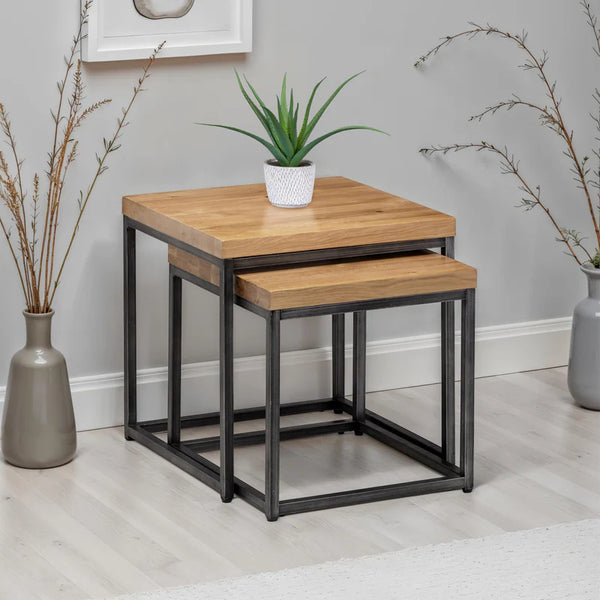 Set of two wooden nesting tables with metal legs in a room setting.
