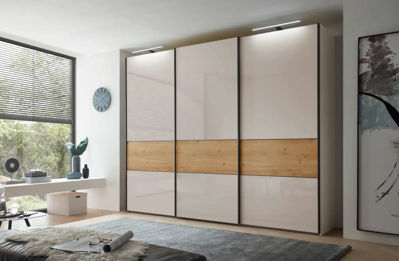 Modern sliding wardrobe with wooden accents in a room with a desk and window.
