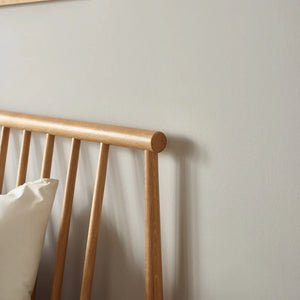 Wooden headboard with a pillow against a plain wall