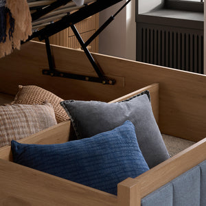 Wooden bed with pillows and a blanket in a room setting