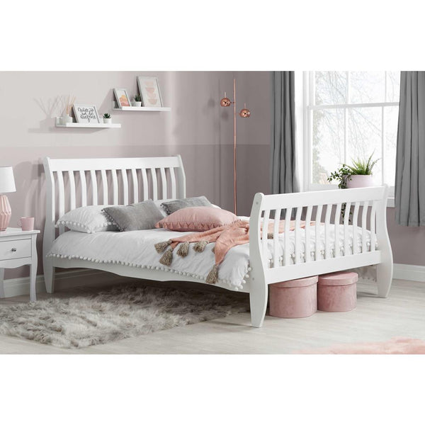 White wooden bed in a bedroom with pink and gray decor