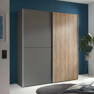 Modern wardrobe with gray and wooden doors in a room with blue walls and a plant.