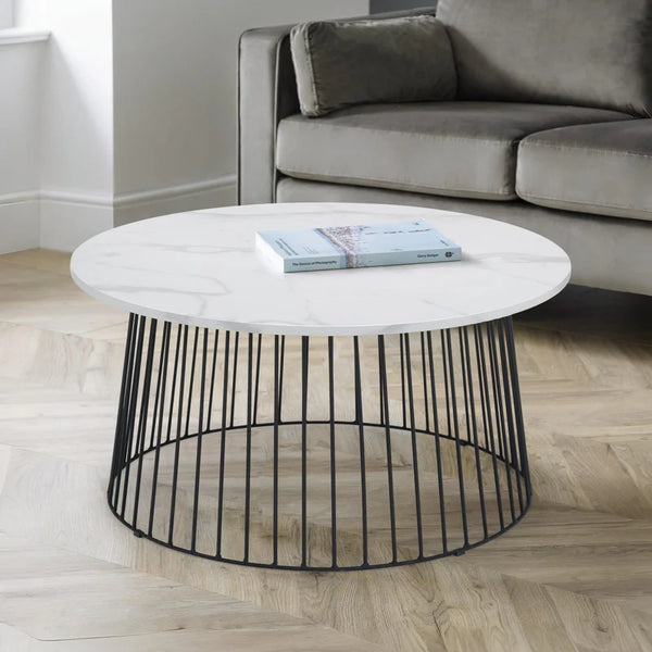 Round coffee table with marble top and black metal base in a living room setting.
