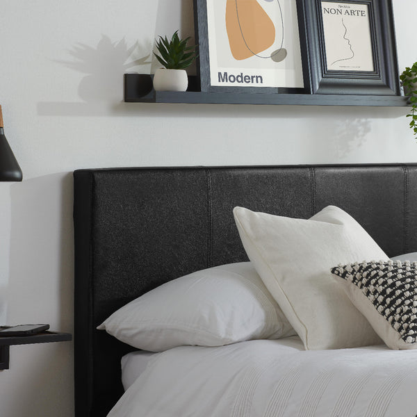 Bedroom with a black headboard, white pillows, and framed art on the wall.