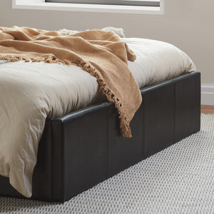 Bed with beige bedding and a brown blanket in a room with a window.