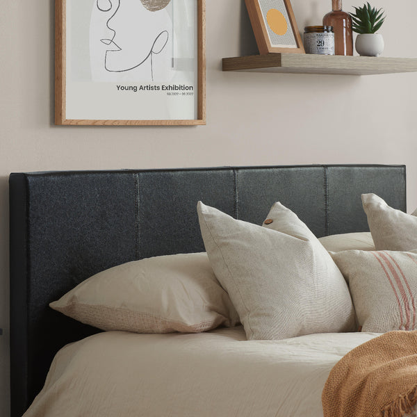 Bedroom with a bed featuring pillows and a headboard, with a shelf and framed art on the wall.