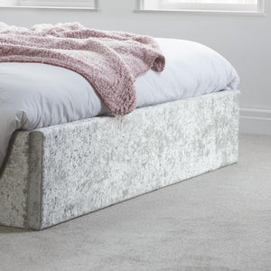 Bed with white bedding and a pink blanket in a minimalistic room.