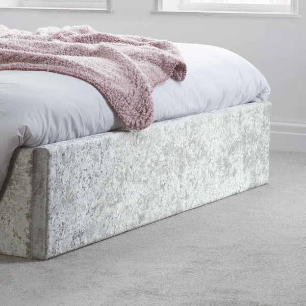 Bed with white bedding and a pink blanket in a minimalistic room.