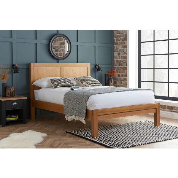 Wooden bed in a bedroom with a blue wall and large window.