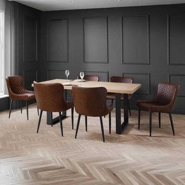Dining room with wooden table and brown chairs against a dark paneled wall.
