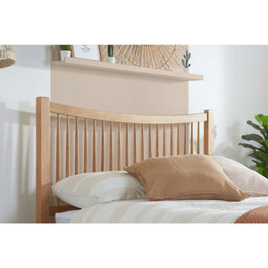 Wooden headboard with pillows on a bed against a white wall.