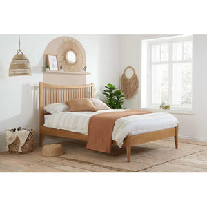 Wooden bed in a bedroom with white walls, a window, and decorative items.