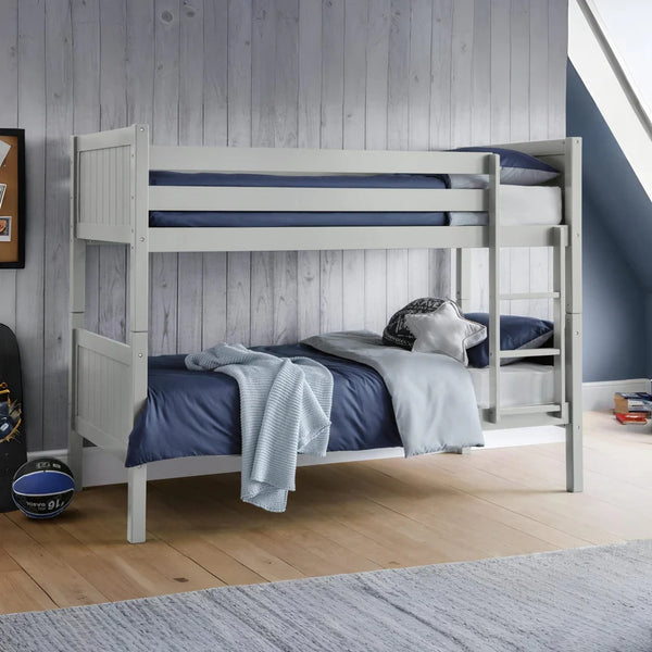 Grey bunk bed with blue bedding in a room with wooden flooring and a gray wall.