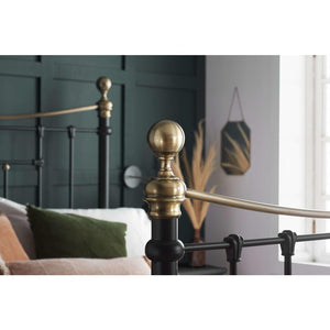Close-up of a bed with brass headboard and pillows in a bedroom setting.