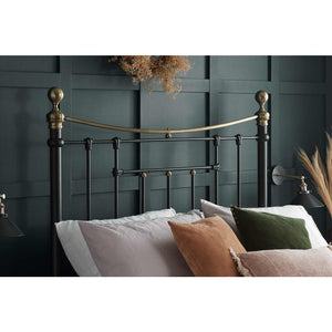 Bed with decorative pillows against a dark green paneled wall