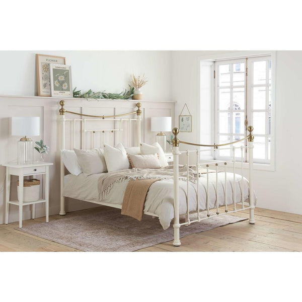 Neatly made bed with white bedding and gold headboard in a bright bedroom.