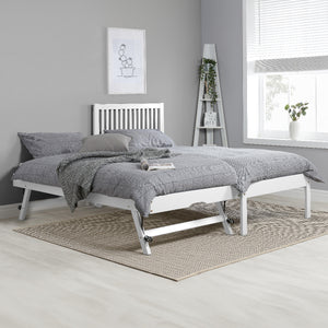 White bed frame with gray bedding in a room with a gray wall and window.