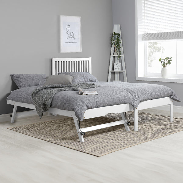 White bed frame with gray bedding in a room with a gray wall and window.
