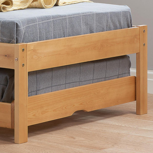 Wooden bed frame with a gray mattress on a wooden floor.