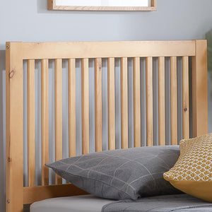 Wooden headboard with two pillows, one gray and one yellow, against a light blue wall.