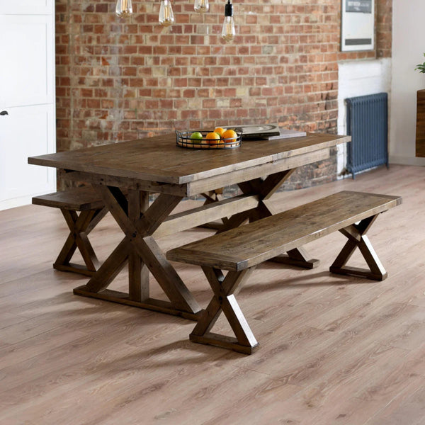 Wooden dining table with benches against a brick wall.