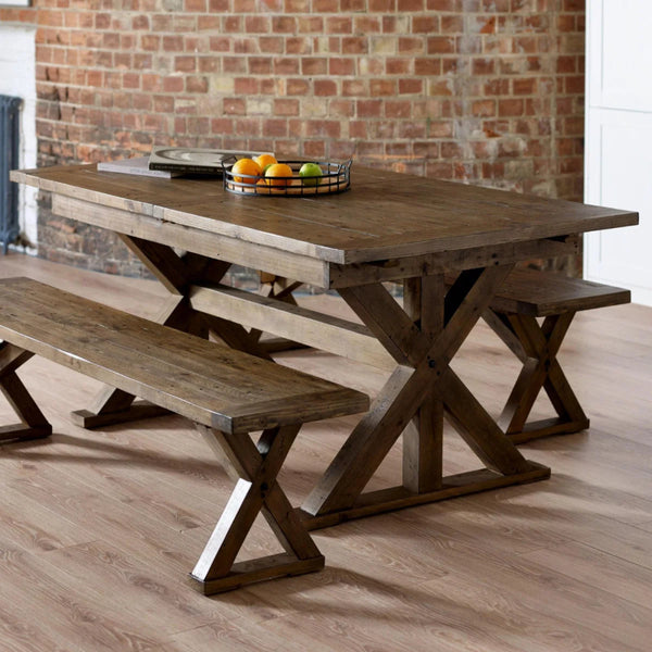 Wooden dining table with benches against a brick wall.