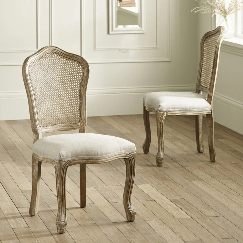 Two wooden chairs with caned backrests and upholstered seats on a white background