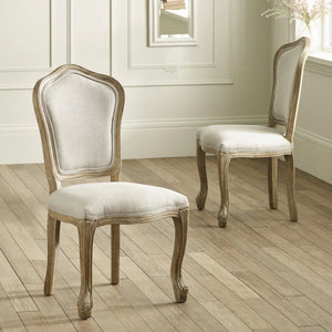 Two wooden chairs with upholstered seats on a wooden floor.