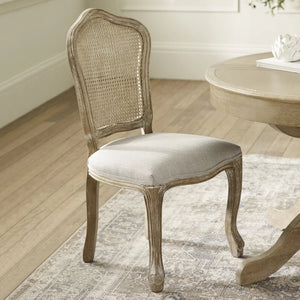 Wooden chair with wicker backrest in a room with a table and rug.