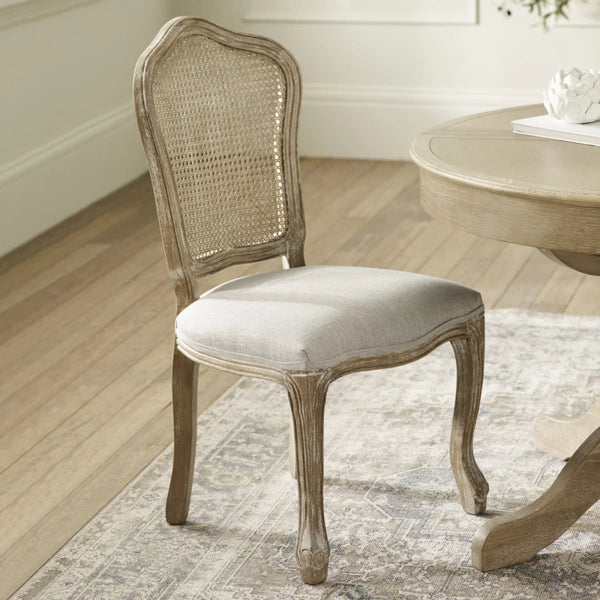 Wooden chair with wicker backrest in a room with a table and rug.