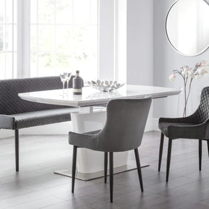 Modern dining room with a white table and gray chairs in a bright room.