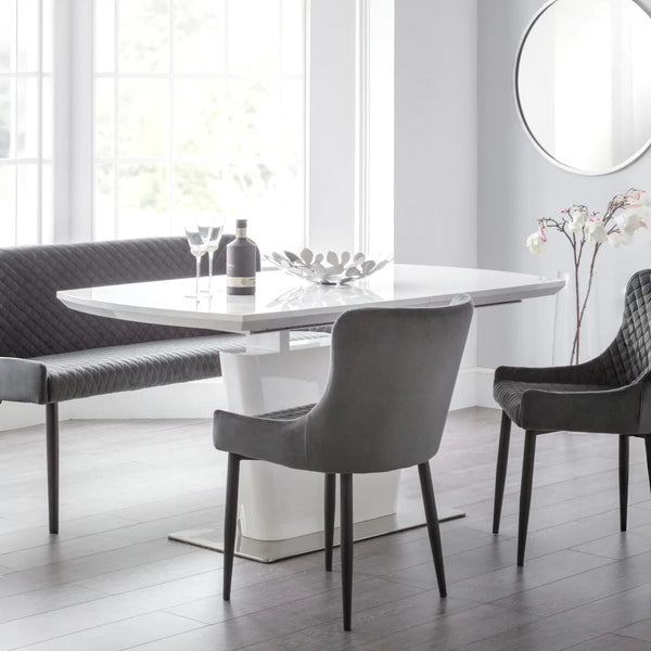 Modern dining room with a white table and gray chairs in a bright room.