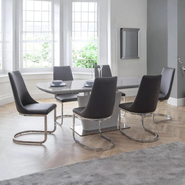 Dining room with a round table and six modern chairs in a well-lit room.