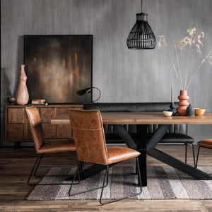Dining area with wooden table and brown leather chairs against a gray wall.