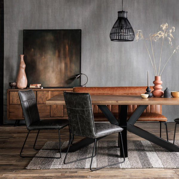 Dining room with wooden table, leather chairs, and decorative elements against a gray wall.