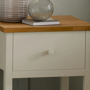 Nighstand with wooden top and single drawer, featuring decorative items.