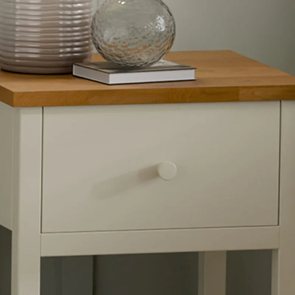 Nighstand with wooden top and single drawer, featuring decorative items.