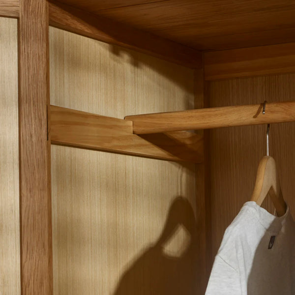 Wooden wardrobe with a hanger holding a white shirt, with a soft shadow on the wooden surface.