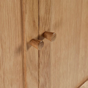 Close-up of wooden cabinet doors with round knobs on a wooden surface.
