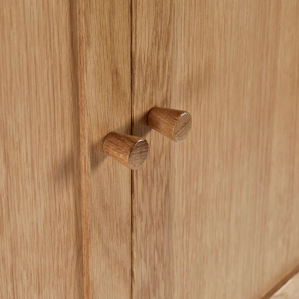 Close-up of wooden cabinet doors with round knobs on a wooden surface.
