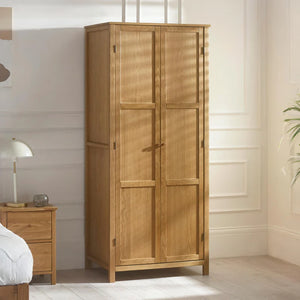 Wooden wardrobe in a bedroom setting with a nightstand and lamp.