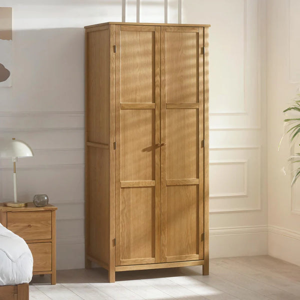 Wooden wardrobe in a bedroom setting with a nightstand and lamp.
