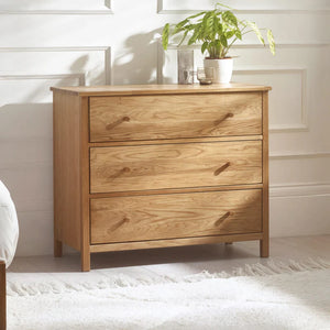 Wooden dresser with three drawers in a bedroom setting