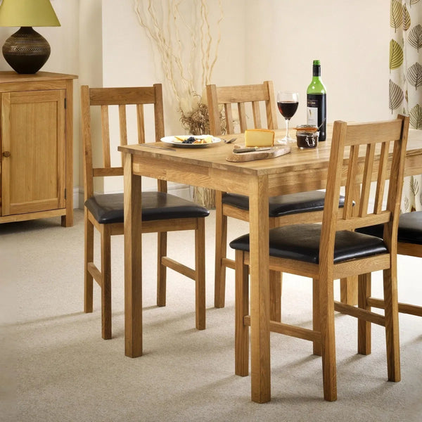 Dining table set with chairs and a bottle of wine in a room.