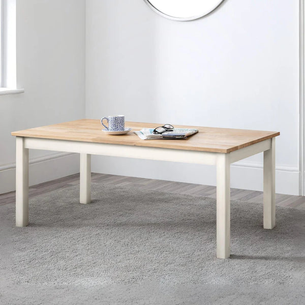 Wooden coffee table with a white base in a room with a light gray carpet.