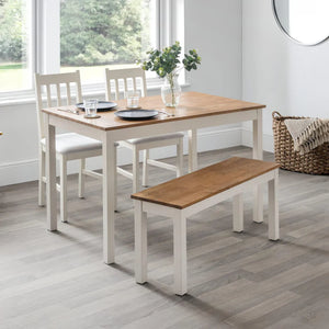 Dining room set with a table, chairs, and bench in a bright room.