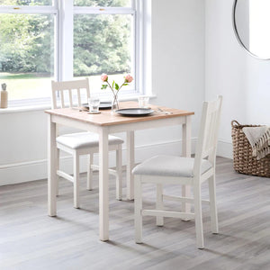 Dining area with a wooden table and white chairs in a bright room.